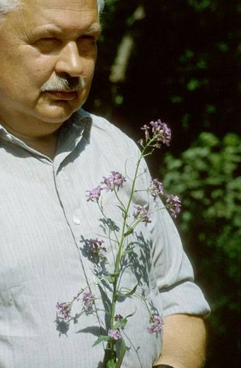 Aristid Lindenmayer, al aire libre, sosteniendo una planta con flores lilas